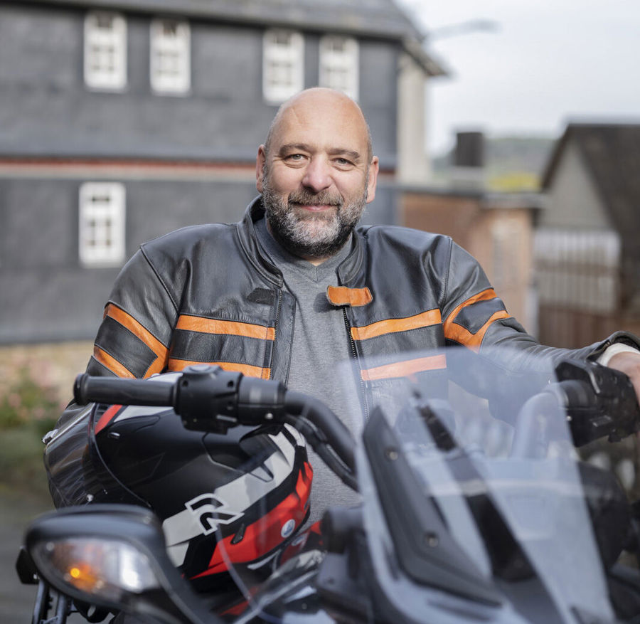 Bilde av Michael sittende på motorsykkelen sin. Michael har MS og blæreproblemer. Han oppdaget at blæren hans var overaktiv og at han måtte tømme blæren oftere enn andre mennesker. 